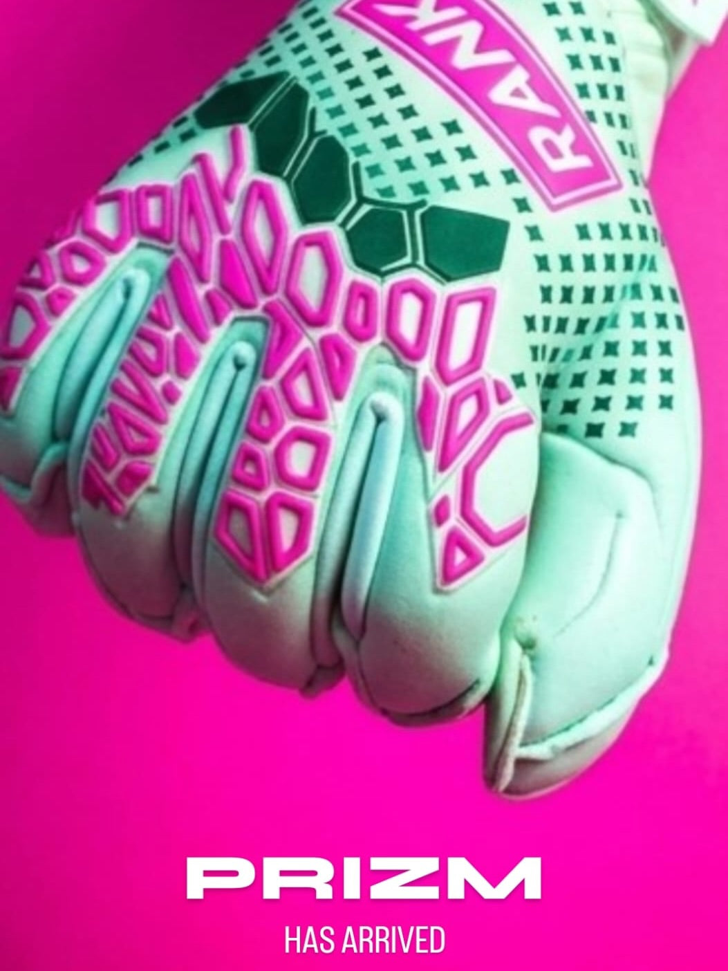 A close-up of a goalkeeper glove in mint green and pink with dark green textured grip patterns, set against a bright pink background with 'PRIZM HAS ARRIVED' text at the bottom.